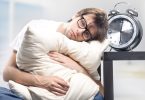 Sad man holding a pillow next to a large clock (Flickr by hang_in_there)