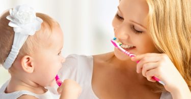 Mom brushes teeth with daughter